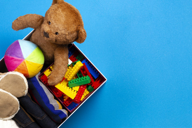 捐款箱与衣服，书籍，儿童玩具在蓝色背景。俯视图图片下载