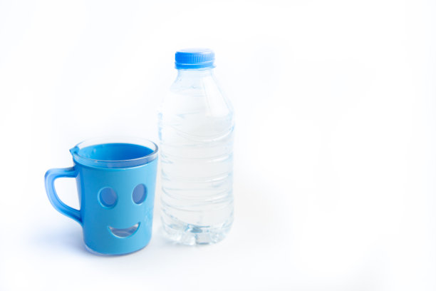 塑料瓶里装着纯净的矿泉水，杯子里装着微笑。特写镜头。图片下载