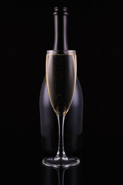 抽象的香槟瓶和玻璃与白色起泡酒在黑色的背景。节日的概念。图片下载