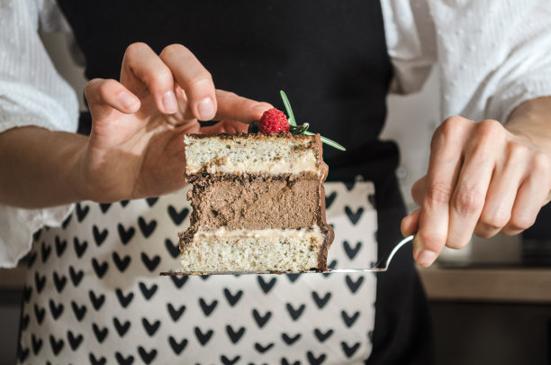 女孩厨师拿着一块蛋糕在厨房里图片下载