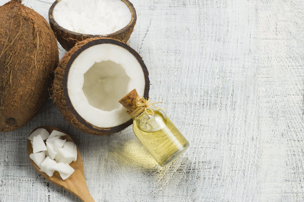 玻璃瓶椰子油与新鲜的椰子水果在乡村的背景，替代疗法医学概念，椰子nucifera图片下载