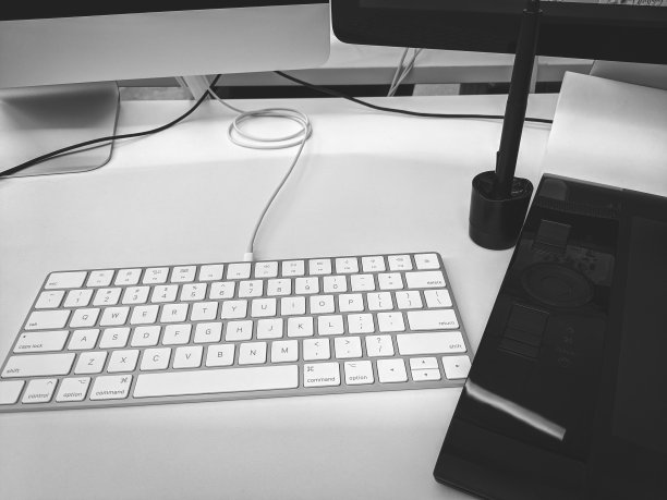 办公室里的工作空间有键盘、平板电脑、笔和两台显示器。电脑桌上的白色和黑色设备图片下载