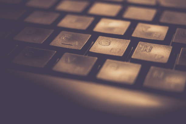 橙色灯光下的黑色键盘，微距照片。图片下载