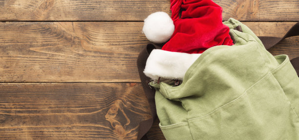 木桌上的复古背包和圣诞帽，假日旅行背景图片下载