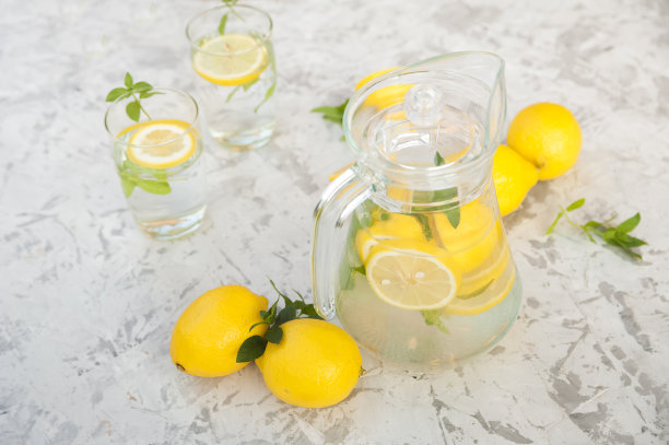 在灯光背景上自制柠檬水的概念。柠檬，玻璃杯，薄荷，水壶和复印空间。夏日清凉饮料柠檬水。图片下载