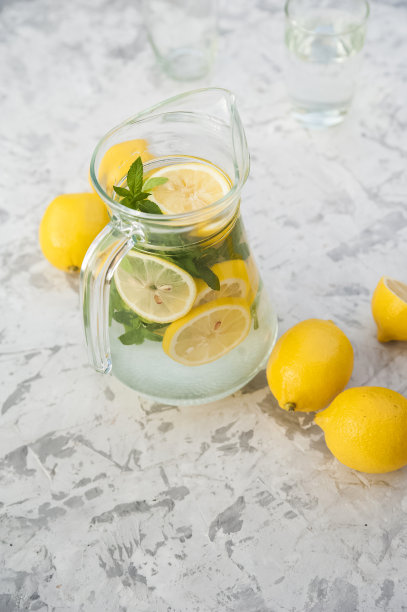 在灯光背景上自制柠檬水的概念。柠檬，玻璃杯，薄荷，水壶和复印空间。夏日清凉饮料柠檬水。图片下载