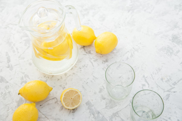 在灯光背景上自制柠檬水的概念。柠檬，玻璃杯，薄荷，水壶和复印空间。夏日清凉饮料柠檬水。图片下载