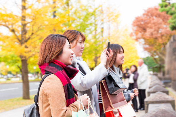 年轻女子在拍摄秋叶图片下载