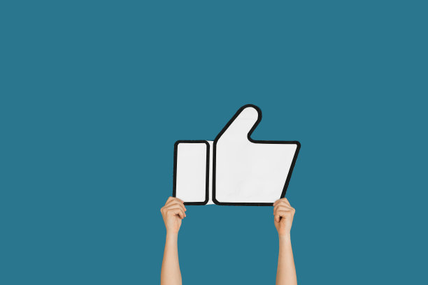 在蓝色的演播室背景上，双手举着“喜欢”的标志图片下载