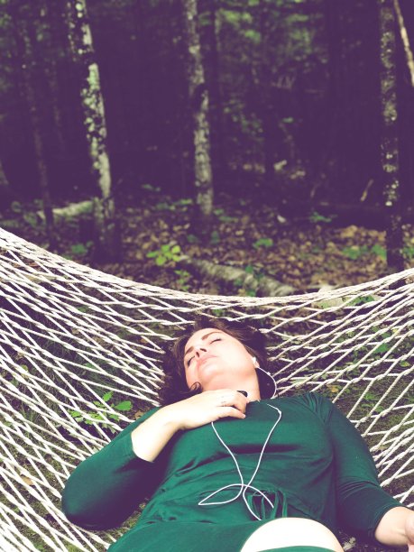 美丽的女人在户外的吊床上用科技放松。图片下载