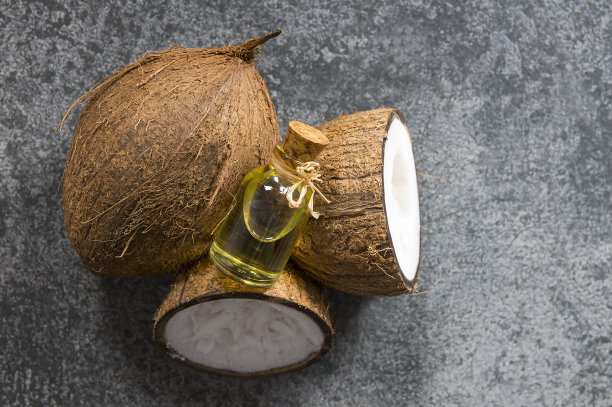 玻璃瓶椰子油与新鲜的椰子水果在乡村的背景，替代疗法医学概念，椰子nucifera图片下载
