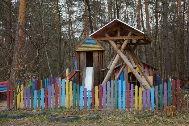 木制儿童游乐场后面的装饰彩色篱笆在一个秋天的公园图片下载