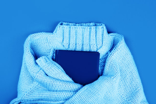 一件柔软的紫色针织毛衣，蓝色背景上有一个红色的笔记本。图片下载