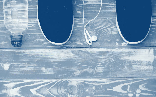 蓝色背景下的运动鞋，耳机和饮用水。运动器材模糊颜色图片下载