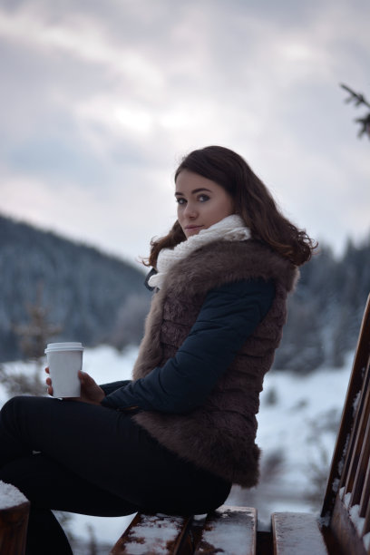 美丽的年轻女孩暖一杯热咖啡或茶。图片下载