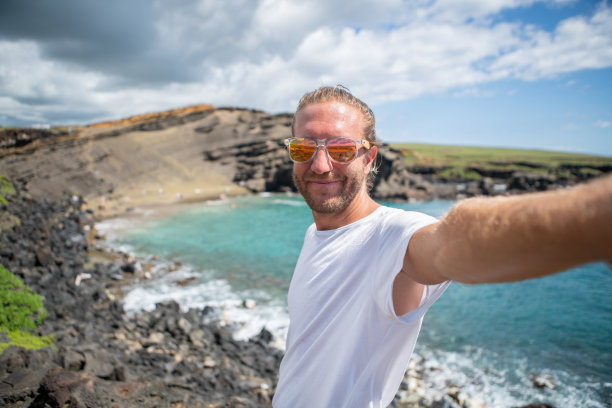 夏威夷，一名徒步旅行者在绿色沙滩上自拍图片下载