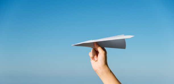 手拿纸飞机，背景是蓝天图片下载