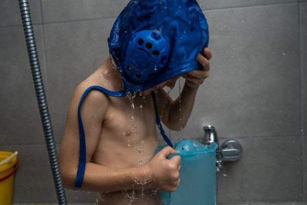 带着水球帽的可爱小孩在浴室洗澡图片下载