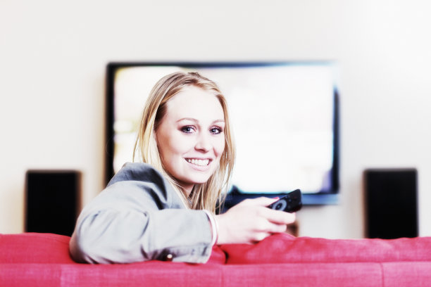 年轻漂亮的金发女郎微笑着，拿着遥控器图片下载