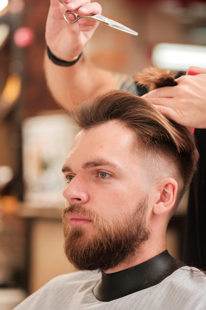 美容服务。一个男人在理发店的发型师那里理发。图片下载