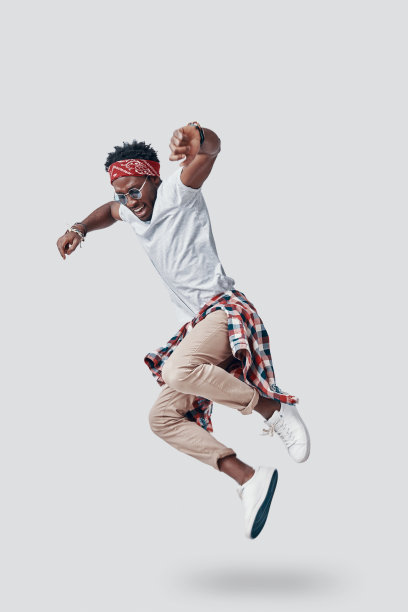 全长顽皮的年轻非洲男子微笑，而盘旋在灰色的背景图片下载