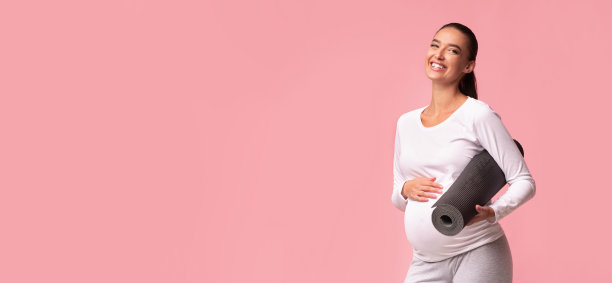 期待女孩拿着体操垫站在粉红色的背景，全景图片下载