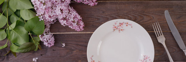 盘子和装饰花的背景上的老式木板。复古背景与丁香花和地方下的文字。从以上观点。平的。餐具。横幅。图片下载