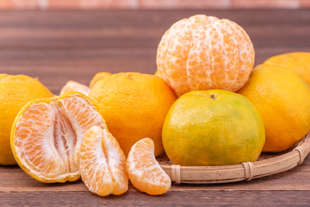 去皮的橘子放在竹筛篮上，深色木桌以红砖墙为背景，中国农历新年水果的设计理念，拉近了距离。图片下载