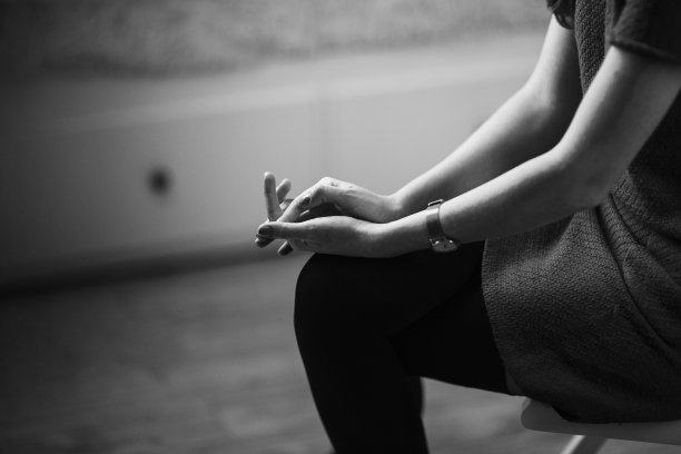 那个女孩紧握着双手坐在椅子上。压力独自等待。黑白图像图片下载