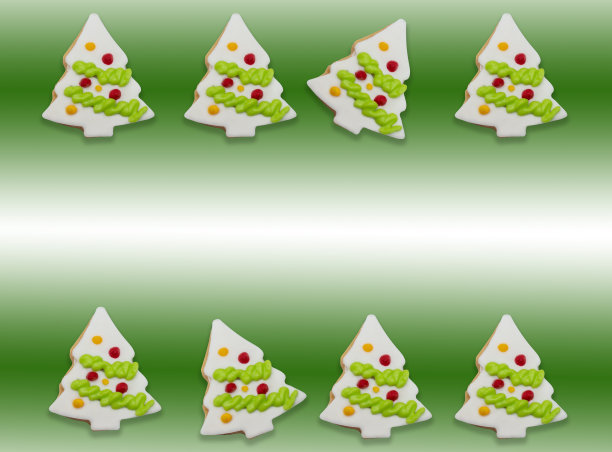 在绿色渐变的背景上，点缀着彩色糖霜的圣诞树形状的釉面饼干。与复制空间在中心点图片下载