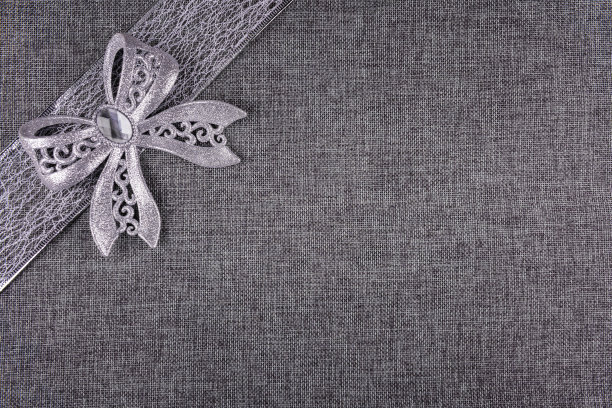 银色的蝴蝶结和灰色粗麻布上的丝带图片下载