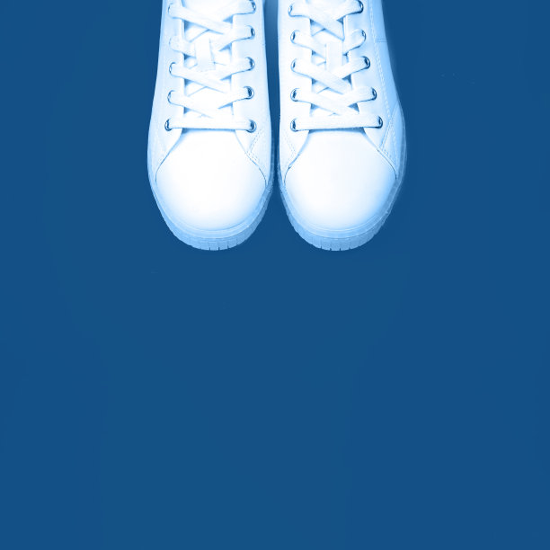 白色的运动鞋躺在蓝色的背景上。图片下载