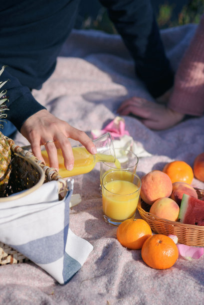 野餐上的婚礼。一个男人把橙汁倒进杯子里图片下载