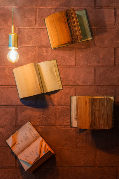 书店或图书馆的书架上堆放着许多旧书，以白色的墙壁为背景。图片下载