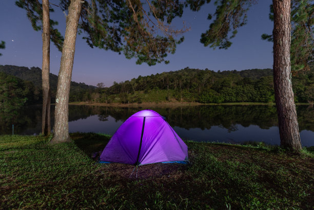 在繁星点点的夜空下，在山林中闪闪发光的露营帐篷图片下载