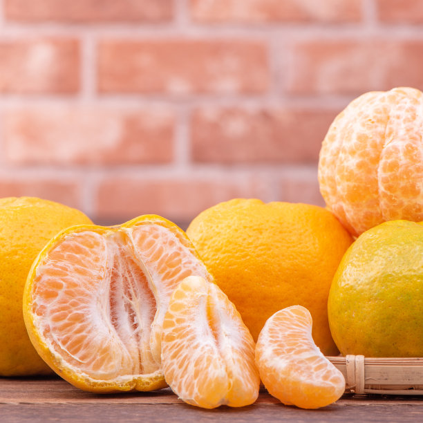 去皮的橘子放在竹筛篮上，深色木桌以红砖墙为背景，中国农历新年水果的设计理念，拉近了距离。图片下载