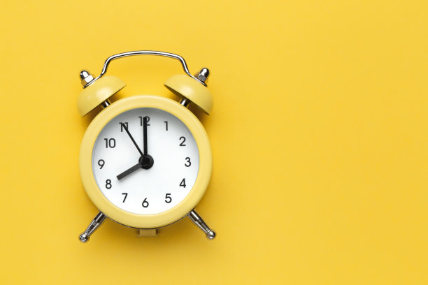 黄色背景上的黄色圆形闹钟。图片下载