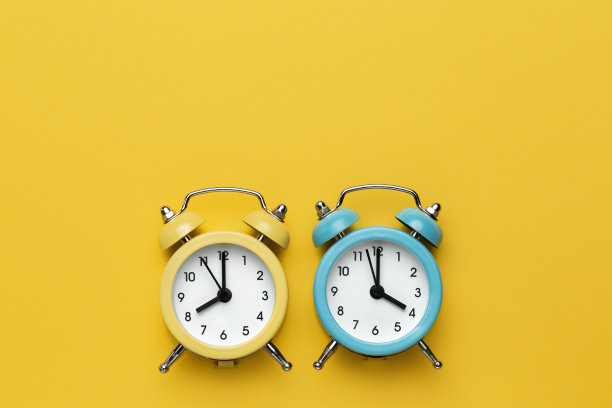 黄色背景上有两个黄色和蓝色的圆形闹钟。图片下载
