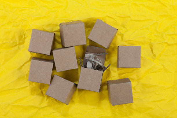 在皱巴巴的黄色背景上散落着一些纸箱图片下载