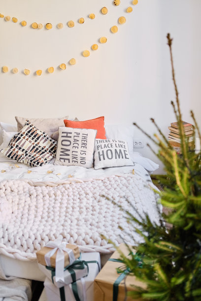 新年房内饰——床、圣诞树、礼物。墙上挂着一个花环。图片下载