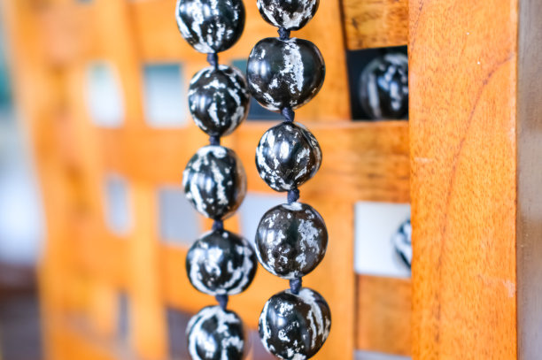 黑色和白色夏威夷库库伊坚果花环项链挂在木制椅子上。图片下载