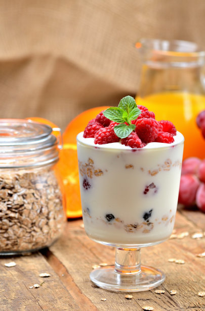 一杯酸奶、燕麦片和新鲜的树莓、薄荷叶、满杯燕麦和橙汁的背景-垂直照片图片下载