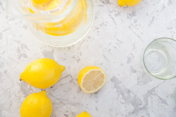 在灯光背景上自制柠檬水的概念。柠檬，玻璃杯，薄荷，水壶和复印空间。夏日清凉饮料柠檬水。图片下载