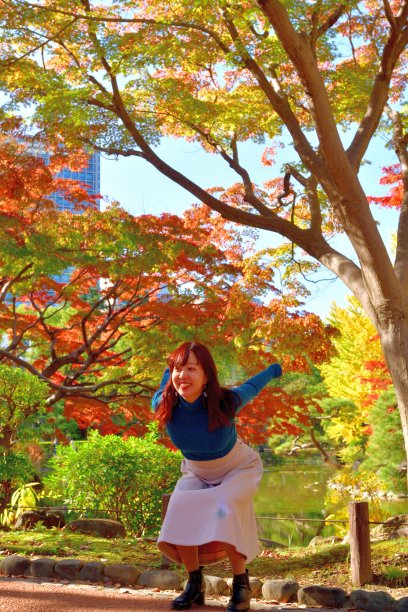在东京日比谷公园欣赏秋叶颜色的年轻日本女性图片下载