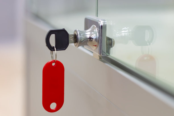 灰色办公玻璃家具上挂着红色标签的锁和钥匙。图片下载