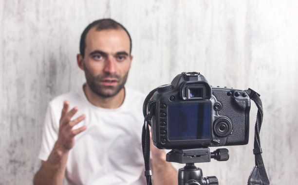 三脚架上的摄像机正在拍摄一个男人。博主图片下载