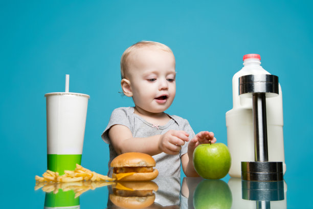 一个小女孩选择了健康的食物，而不是有害的，然后抓了一个苹果。图片下载