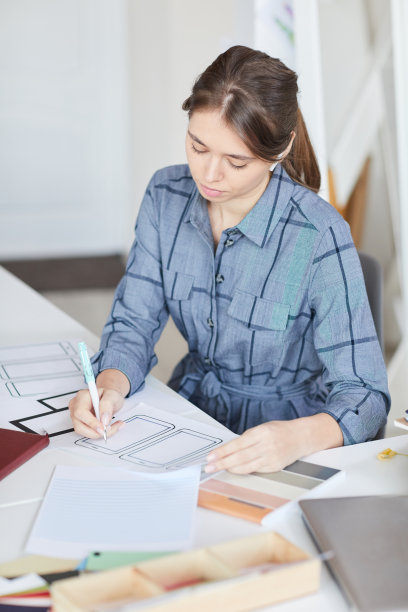 严肃美丽的女孩专注于ui设计坐在桌子上，为小工具创造界面图片下载