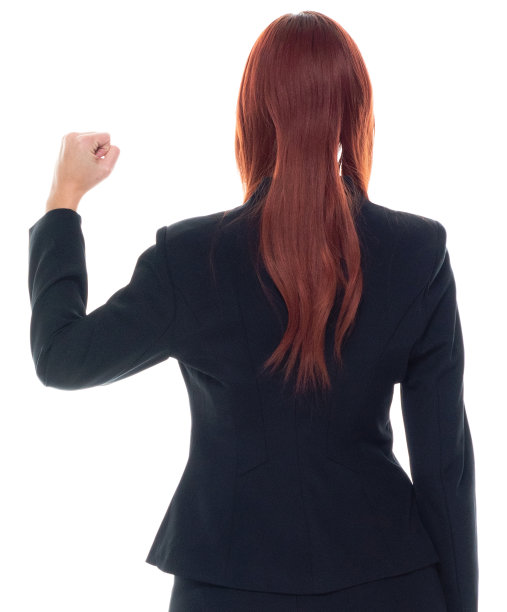 背影/背影/一人/腰部以上/ 20-29岁的成年人照片漂亮的红发/长发白人女性/年轻女性商人/商人穿着商务装/套装站在那里，兴奋/成功和欢呼图片下载
