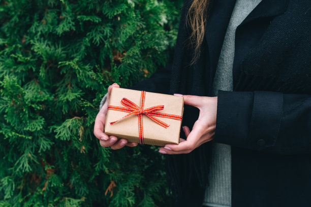 赠送用牛皮纸和红丝带包裹的圣诞或生日礼物的女人。金钟柏背景图片下载